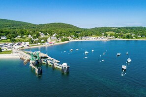 A coastal town with a marina, boats, and a road leading to a parking area.