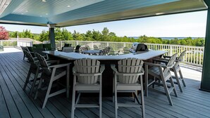A covered outdoor deck with a table and chairs, overlooking a scenic view. - Resort style, family friendly getaway! (Lincolnville)