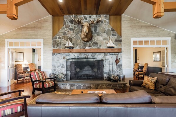 A cozy living room with a stone fireplace, leather sofa, and wooden accents. - Resort style, family friendly getaway! (Lincolnville)