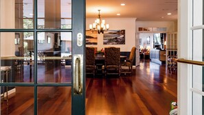 A dining area with a chandelier, wooden flooring, and a view of the kitchen. - Resort style, family friendly getaway! (Lincolnville)