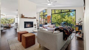 A modern living room with a fireplace, large windows, and a cozy seating area. - Luxury Desert Retreat w/ Hot tub + Fire Pit! (Sedona)
