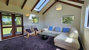 A living room with a glass coffee table, two armchairs, a sofa, and a ceiling fan. - Charming Beach House (Ruby Bay)