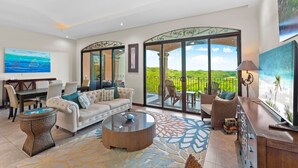A spacious living room with a large sofa, a coffee table, and a dining area with chairs and a table. - Treetop Ocean View Penthouse - Jobo 15 (Brasilito)