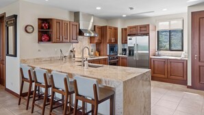 A modern kitchen with a large island, wooden cabinets, stainless steel appliances, and a window with a view. - Treetop Ocean View Penthouse - Jobo 15 (Brasilito)