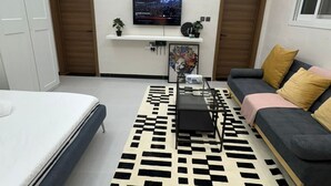 Un soggiorno moderno con una TV a schermo piatto, un divano, un letto e un tappeto decorato.
