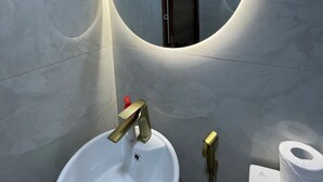 Un bagno con un lavandino bianco, uno specchio e un water.