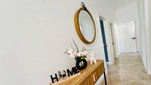 Um corredor com uma mesa consola de madeira, um espelho e uma composição decorativa de flores e uma estatueta de coelho.