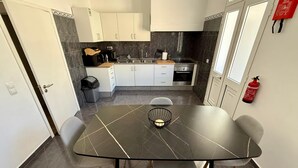 Uma cozinha moderna com armários brancos, bancada preta e pia de aço inoxidável.