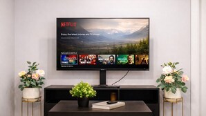 Televisor de pantalla plana montado en la pared mostrando series populares de Netflix.