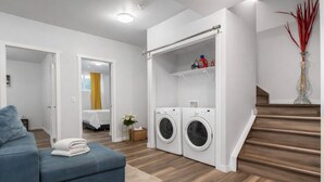 Un apartamento moderno con un sofá azul, una lavadora y una escalera.