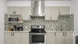 Una cocina moderna con estufa de acero inoxidable, microondas y salpicadero de azulejos.