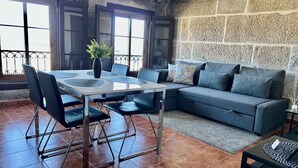 A dining area with a table and chairs, a sofa, and a stone wall. - Charming apartment in the best area of downtown Vigo (Vigo)