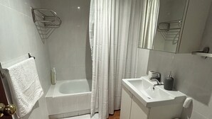 A bathroom with a bathtub, toilet, sink, and a mirror. - Charming apartment in the best area of downtown Vigo (Vigo)