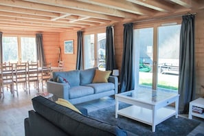 A cozy living room with a sofa, a coffee table, and a dining area with chairs and a table. - A perfect stay in a modern 4 bedroom chalet, close to the village center! (Samoëns)