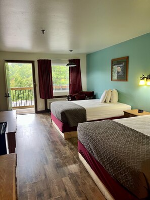 A hotel room with two beds, a desk, a window with curtains, a balcony, and a framed picture on the wall. - 2 Double Queen Condos Free Shuttle to Silver Dollar City (Branson)