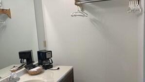 Ett badrum med ett vitt handfat, en spegel, en handdukshängare, en kaffebryggare och en papperskorg.