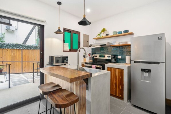 A modern kitchen with a central island, stainless steel appliances, and a wooden bar stool seating area.