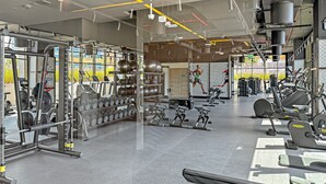 Een moderne sportschool met diverse fitnessapparatuur, waaronder loopbanden, krachttoestellen en gewichten.