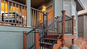 A wooden staircase with a metal railing leading to a porch area.