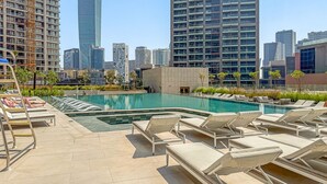Un espace piscine aménagé sur le toit, avec des chaises longues et une vue sur le panorama urbain.