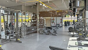 Une salle de sport moderne équipée de divers appareils d’exercice, notamment des tapis de course, des appareils de musculation et des poids libres.