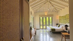Une pièce spacieuse avec un plafond haut, un lit, un banc et une table.