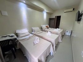 Habitación de hotel con dos camas, una mesita, una silla y un aire acondicionado.
