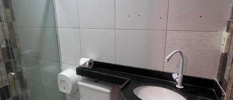 A bathroom with a toilet, a sink, and a shower area.