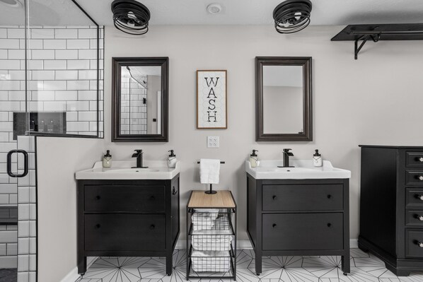 A modern bathroom with two sinks, dark cabinets, and a geometric patterned floor.