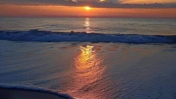 Un coucher de soleil sur l’océan, avec des rayons de lumière se répandant dans le ciel.