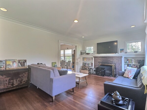 A living room with a fireplace, a television mounted above it, and a bookshelf filled with books.