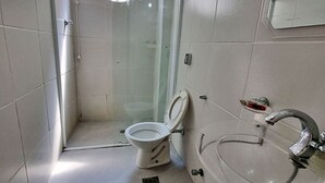 A bathroom with a toilet, a glass shower enclosure, and a sink. - Renovated apartment, just 250m from the sea, fast Wi-Fi, close to the Aquarium, for 4 people (Guarujá)