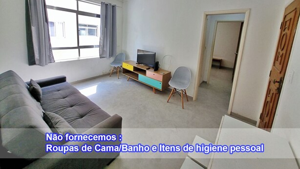 A living room with a sofa, TV, and chairs. Text indicates missing items like bed linens and personal hygiene items. - Renovated apartment, just 250m from the sea, fast Wi-Fi, close to the Aquarium, for 4 people (Guarujá)