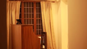 A room with a wooden desk, a chair, a ceiling fan, and a window with curtains. - Fort Verdant Homestay (Kochi)
