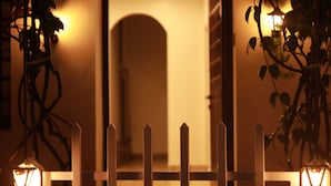 A warmly lit entrance with a wooden gate and a pathway leading to an interior space. - Fort Verdant Homestay (Kochi)