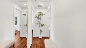 A hallway with wooden flooring, white walls, and a potted plant. - Modern Comfort in the Heart of NYC (Yonkers)