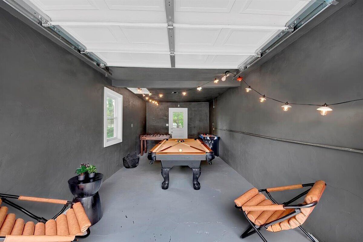 A pool table room with a ceiling fan, string lights, and two pool tables.
