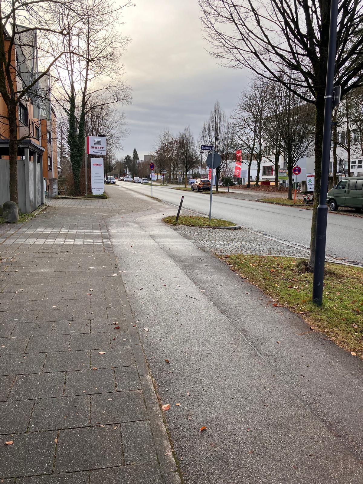 Un trottoir dallé, situé à côté d’une route, avec un panneau indiquant un service d’entretien SEAT.