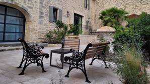 A stone building with a courtyard featuring outdoor furniture and plants. - Self-contained studio located in Mas Saint-Raphaël (Solérieux)
