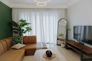 Una sala moderna con sofá, mesa de centro, televisor y plantas.