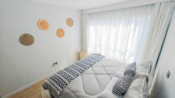 Un dormitorio con una cama, una ventana con cortinas ligeras y tres adornos circulares en la pared.