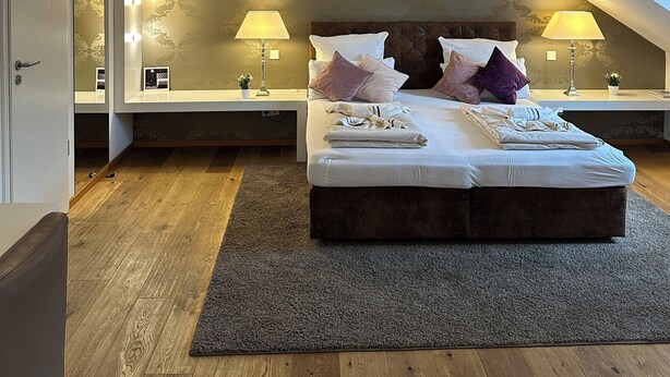 A modern bedroom with a large bed, two bedside tables with lamps, a mirror, and a ceiling fan. - Haven - Helvetia Suites Düsseldorf City (Düsseldorf)