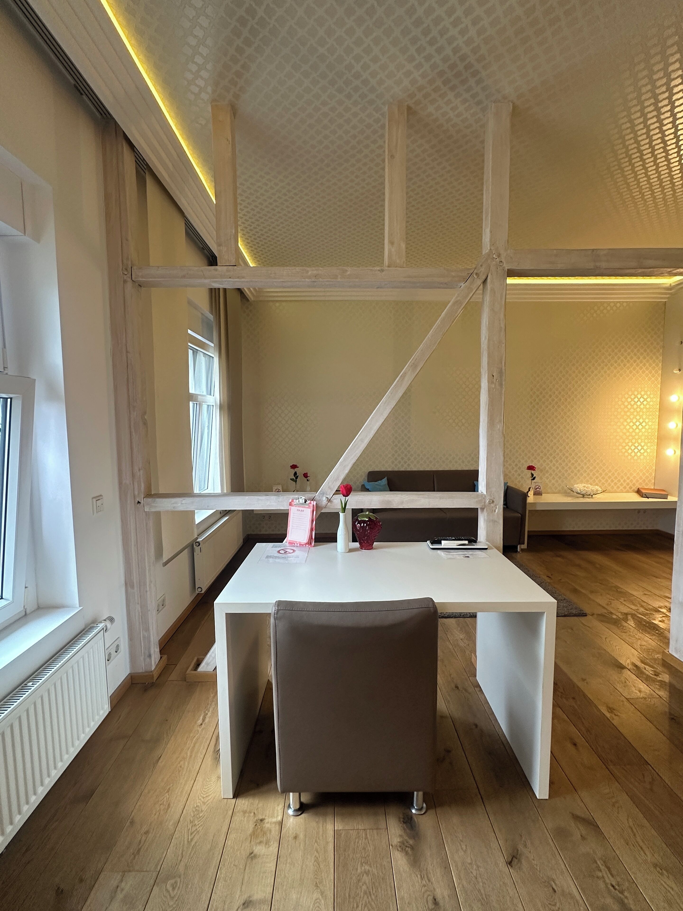A modern office space with a white desk, a brown chair, and a wooden floor.