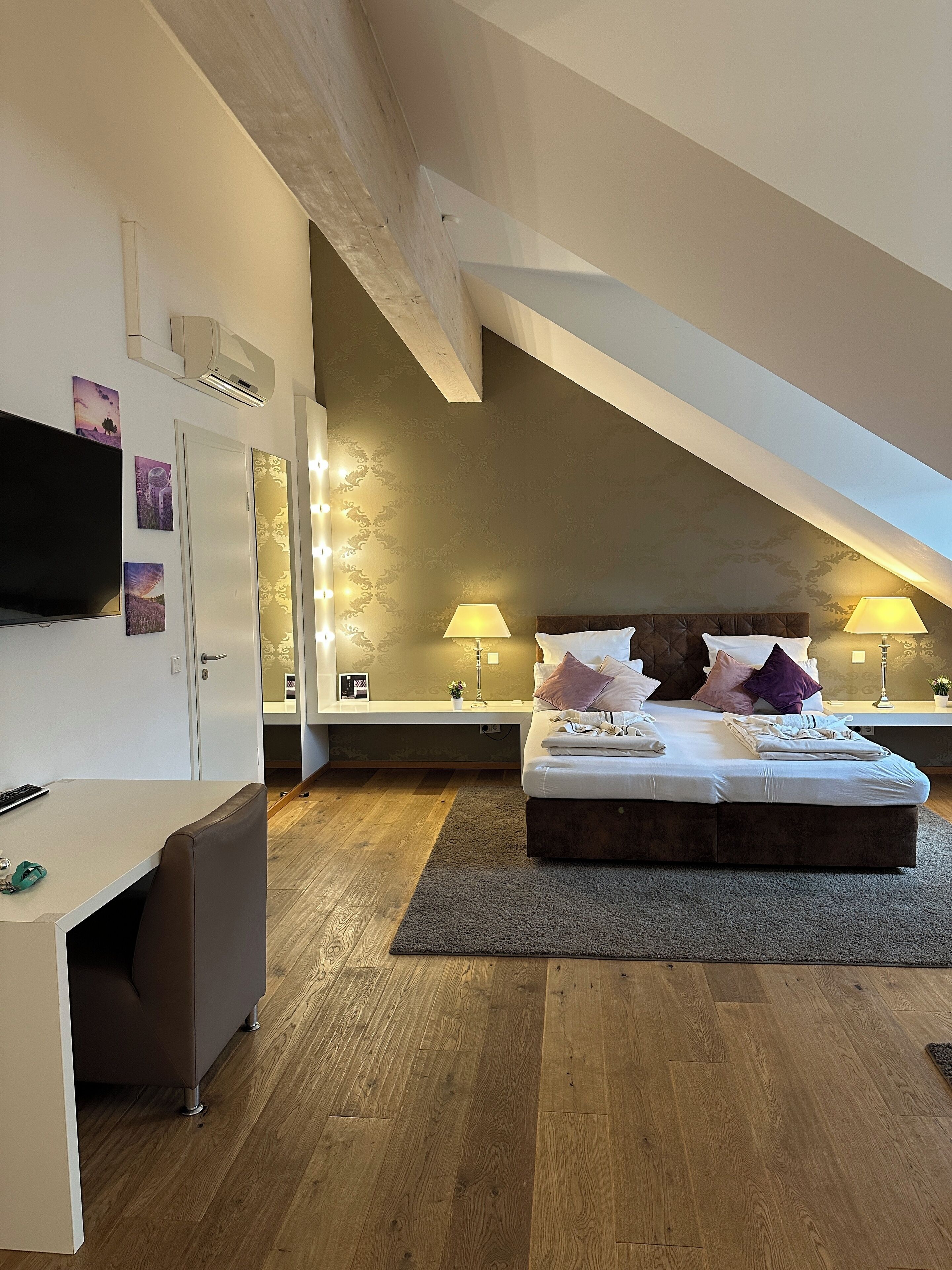 Een slaapkamer met een bed, nachtlampjes, een bureau en een televisie.