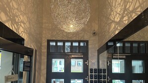 A reception area with a modern chandelier, double doors with frosted glass panels, and a security keypad. - Haven - Helvetia Suites Düsseldorf City (Düsseldorf)