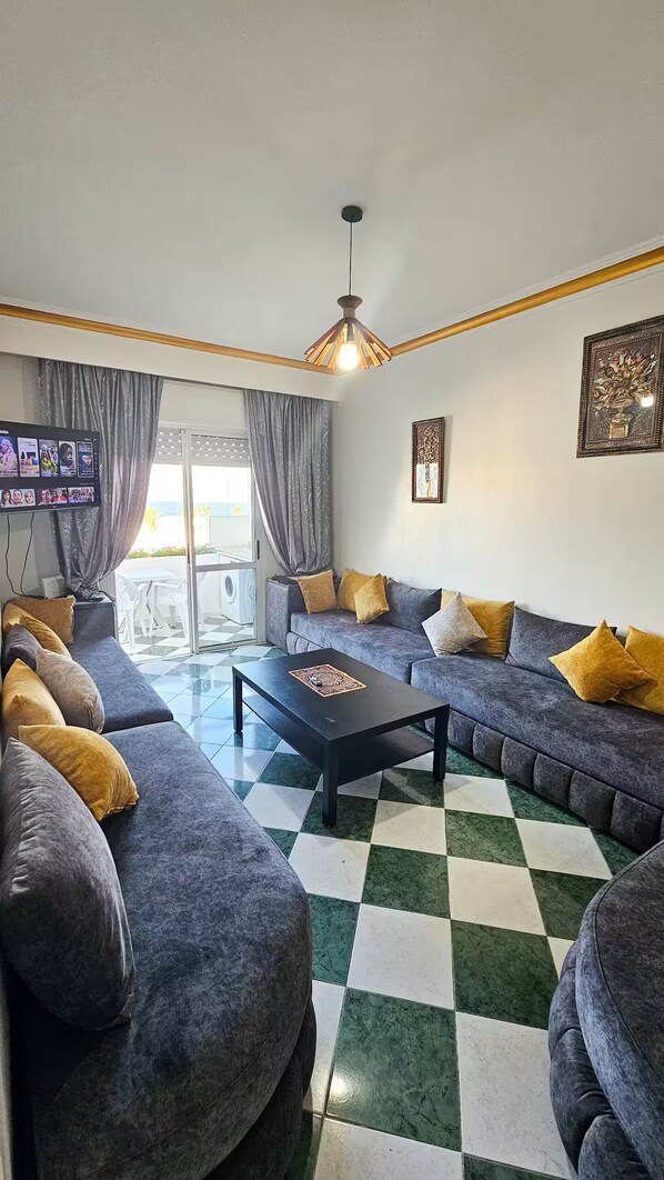Un salón con suelo a cuadros, sofás grises y una mesa de centro.