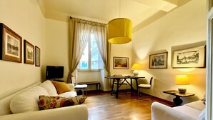 A cozy living room with a sofa, a dining table, and a TV. - Spanish Steps from my window (ROMA)