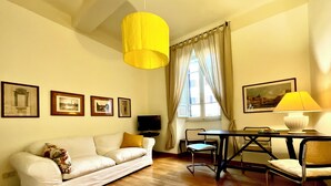 A living room with a sofa, a dining table with chairs, a TV, and framed pictures on the wall. - Spanish Steps from my window (ROMA)