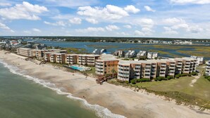 Un hotel frente a la playa con varias edificaciones, piscina y acceso directo a la arena.