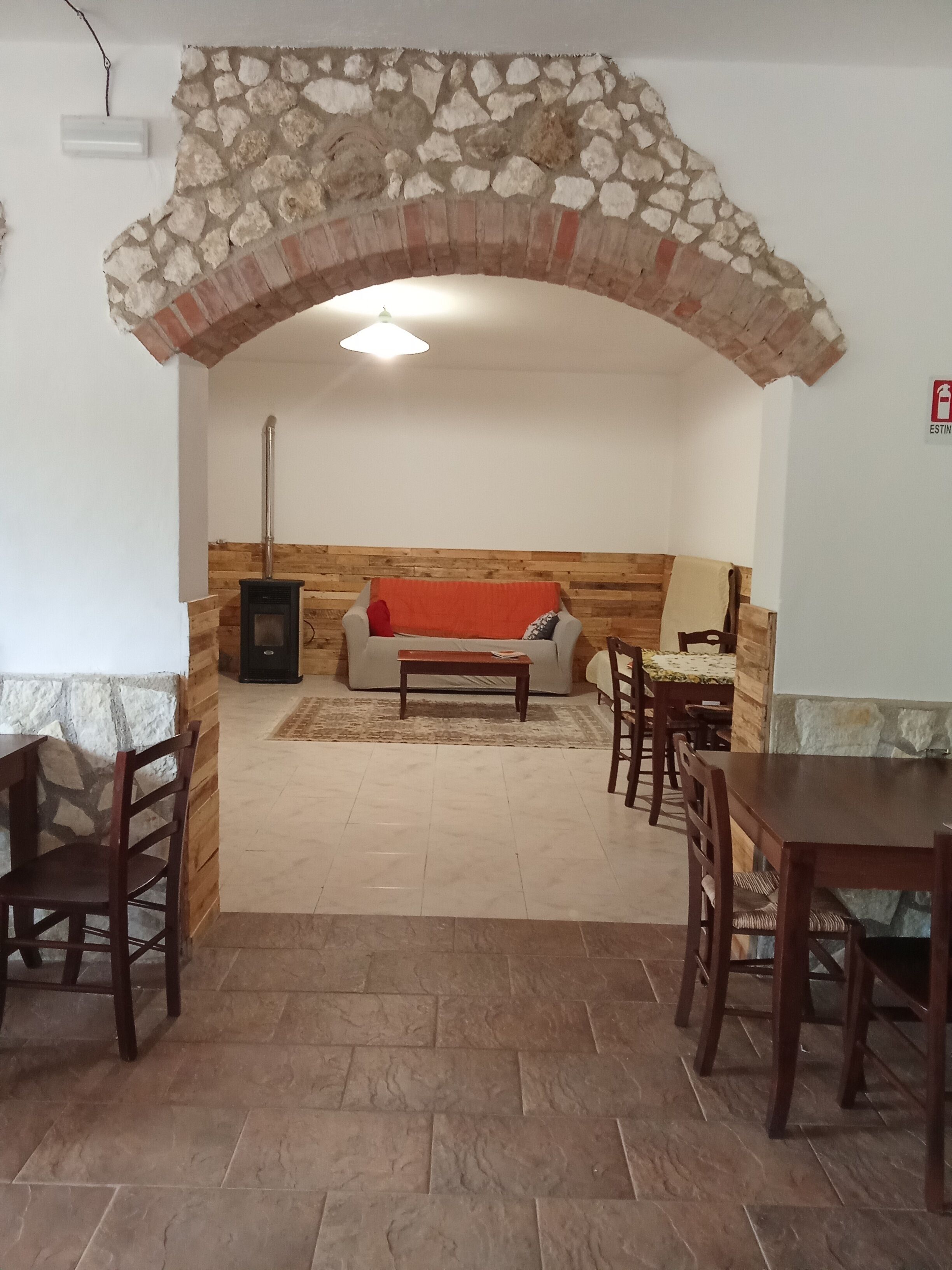 Un salon chaleureux agrémenté d’une arche en pierre, d’une cheminée, d’un canapé et d’une table à manger avec des chaises.